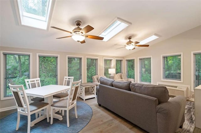 living room with lofted ceiling with skylight, a ceiling fan, a wall mounted air conditioner, and wood finished floors