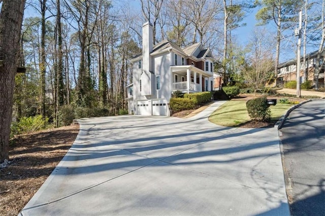 view of side of property featuring a garage, a chimney, and concrete driveway