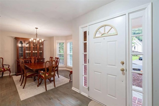 entryway featuring dark wood-style flooring, a notable chandelier, and baseboards