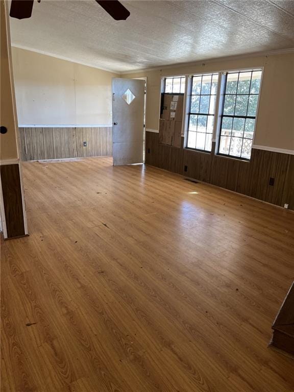 interior space featuring hardwood / wood-style floors, a textured ceiling, wooden walls, and ceiling fan