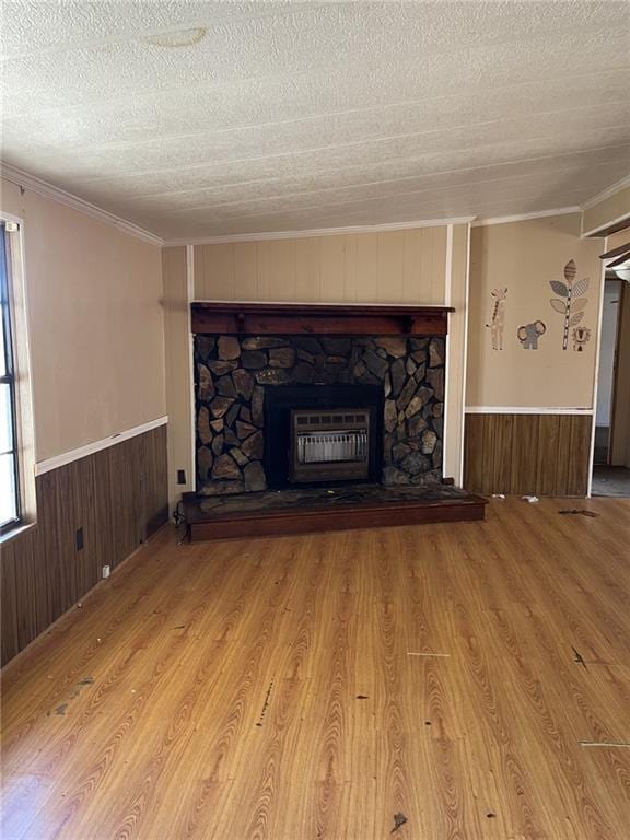 unfurnished living room featuring crown molding, a fireplace, light hardwood / wood-style flooring, and a textured ceiling