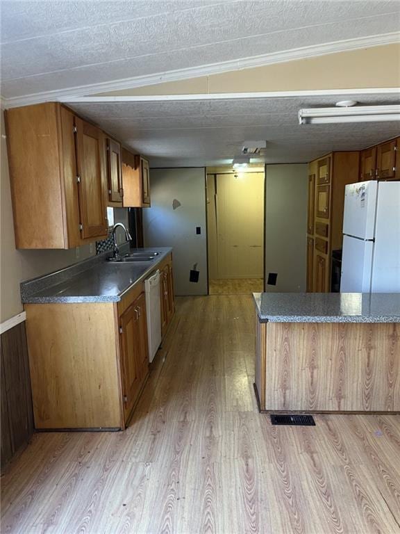 kitchen featuring sink, a textured ceiling, white appliances, and light hardwood / wood-style floors