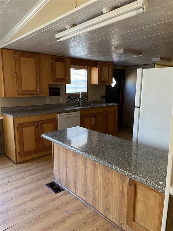 kitchen with white appliances, light hardwood / wood-style floors, sink, and a textured ceiling