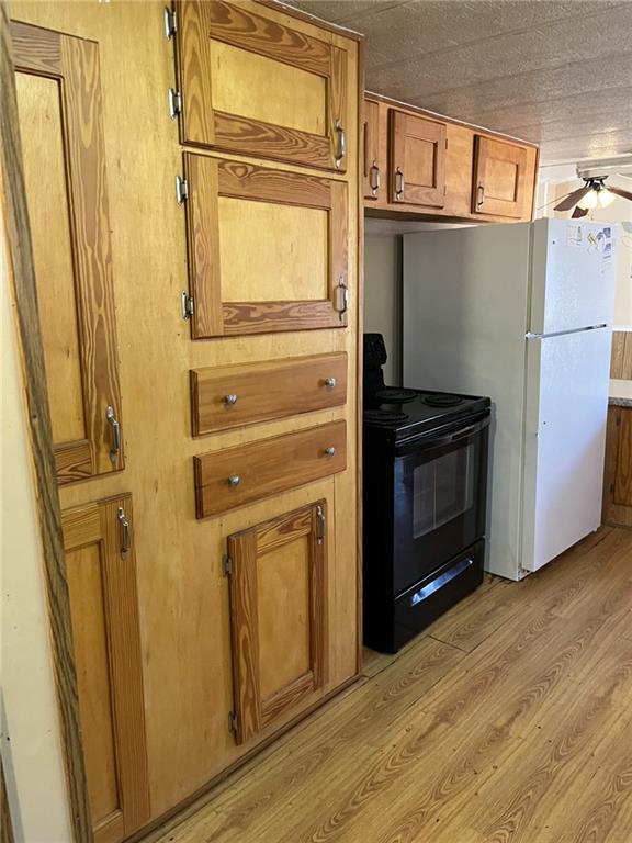 kitchen with white refrigerator, black range with electric stovetop, ceiling fan, and light wood-type flooring