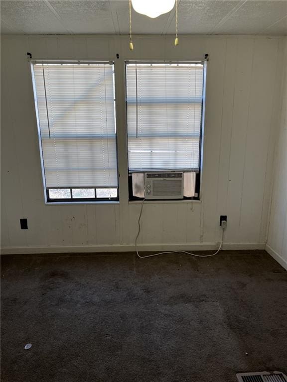 carpeted empty room featuring plenty of natural light, cooling unit, and a textured ceiling