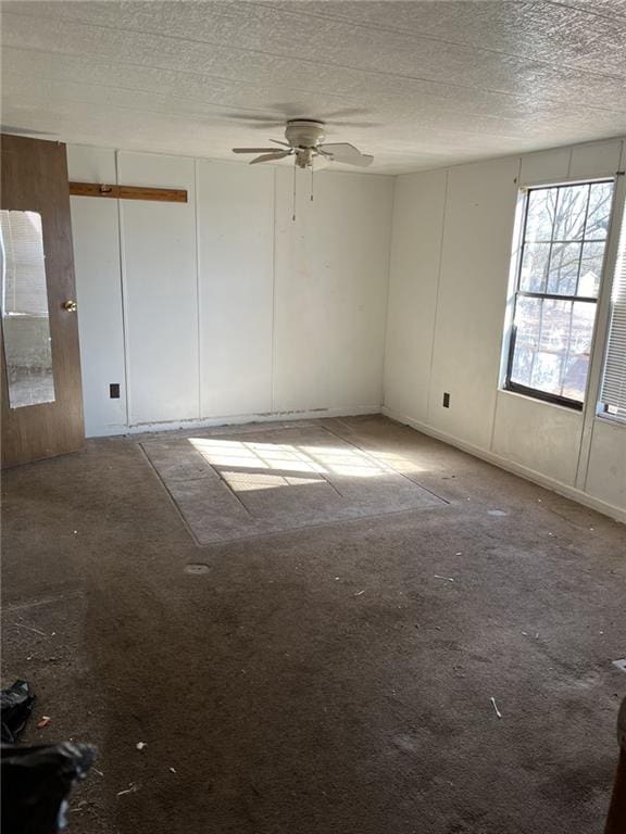 empty room with ceiling fan and a textured ceiling