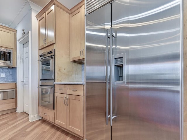 kitchen with tasteful backsplash, light brown cabinets, built in appliances, light wood-style flooring, and a warming drawer