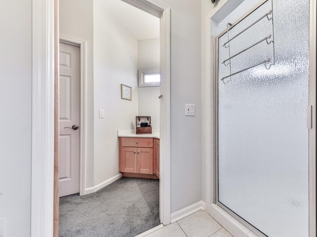 full bath featuring tile patterned floors, baseboards, vanity, and a shower stall