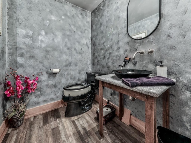 bathroom with toilet, wood finished floors, baseboards, and a sink