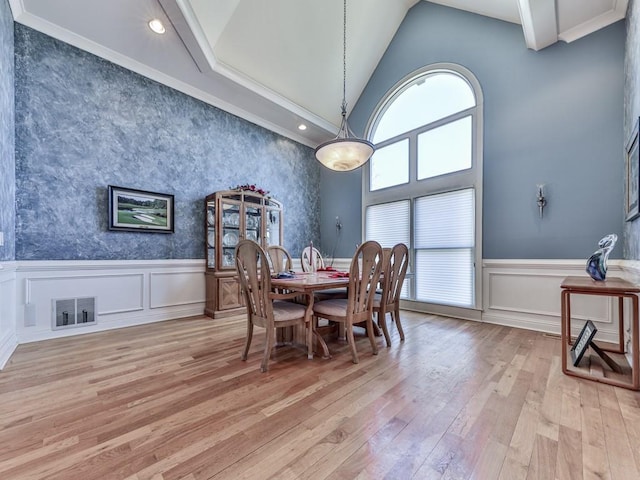 dining space featuring a wainscoted wall, high vaulted ceiling, visible vents, and light wood-type flooring