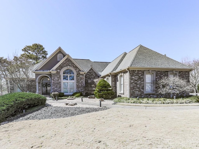 view of front of house featuring brick siding and roof with shingles