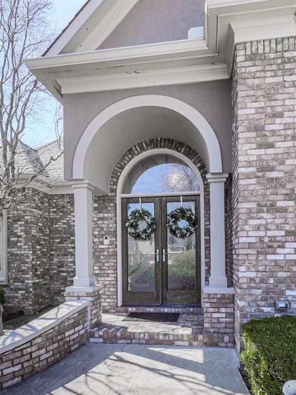 doorway to property with french doors, brick siding, and stucco siding