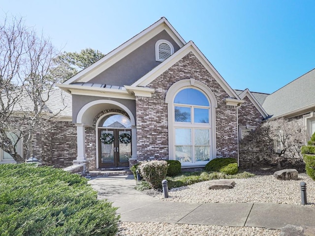 view of front of property with brick siding, stucco siding, and french doors