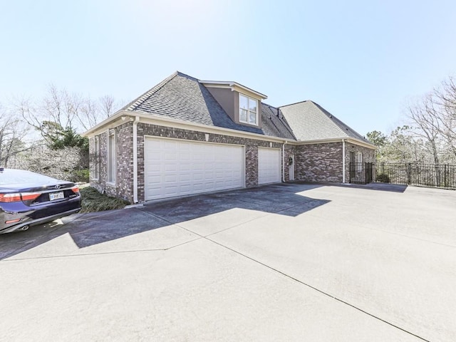 view of home's exterior with brick siding, a shingled roof, fence, a garage, and driveway