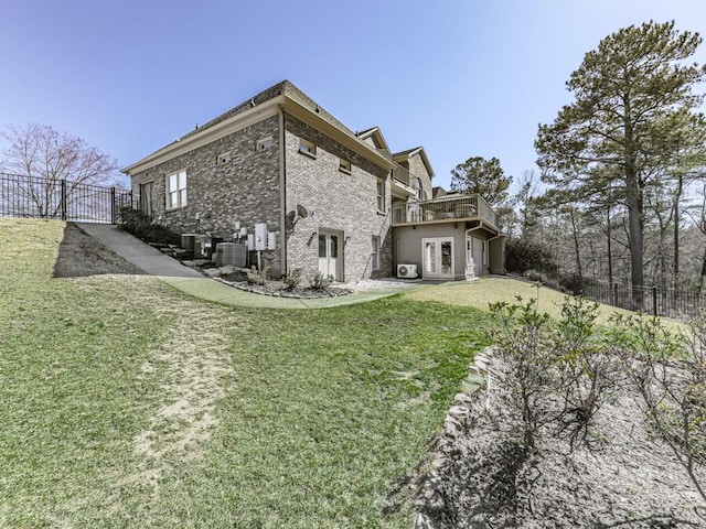 rear view of house with a yard, fence, brick siding, and central AC