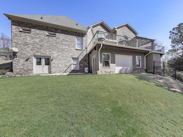 rear view of property featuring fence, stucco siding, a lawn, a garage, and a balcony