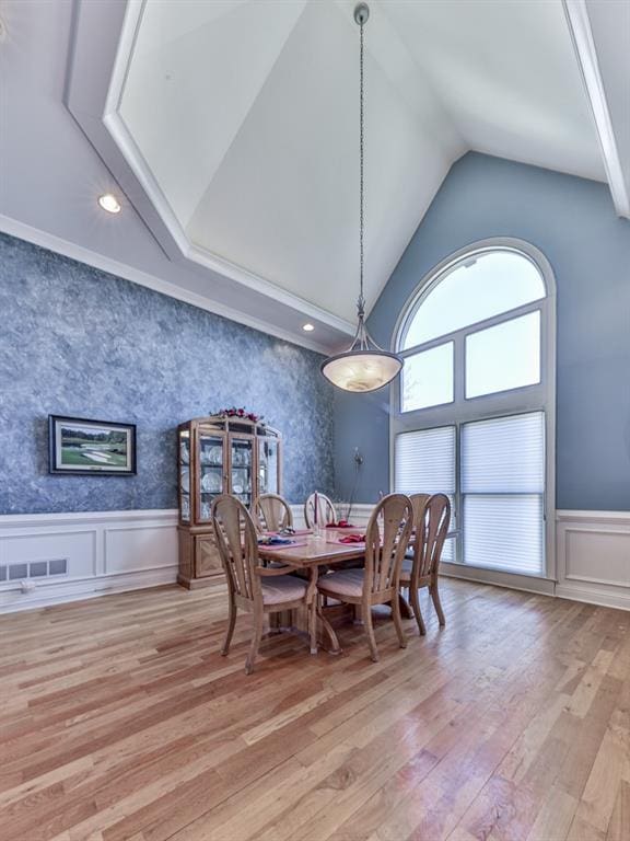 dining room featuring visible vents, light wood finished floors, wallpapered walls, wainscoting, and a decorative wall