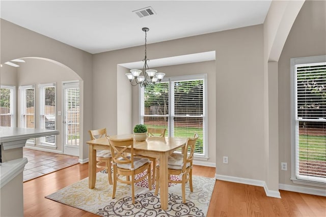 1712 Bonnabel Trce NE, Marietta, GA 30066 - dining room with a chandelier, arched walkways, light wood finished floors, and baseboards