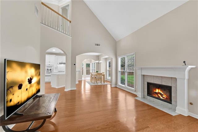 1712 Bonnabel Trce NE, Marietta, GA 30066 - living area featuring arched walkways, high vaulted ceiling, light wood finished floors, a fireplace, and baseboards
