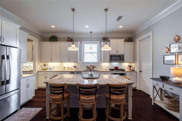 kitchen featuring white cabinetry, stainless steel appliances, light stone counters, a kitchen island, and decorative light fixtures