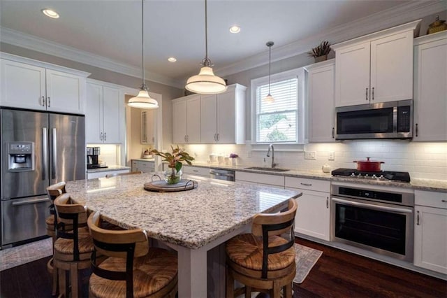 kitchen featuring stainless steel appliances, sink, a kitchen island, and white cabinets