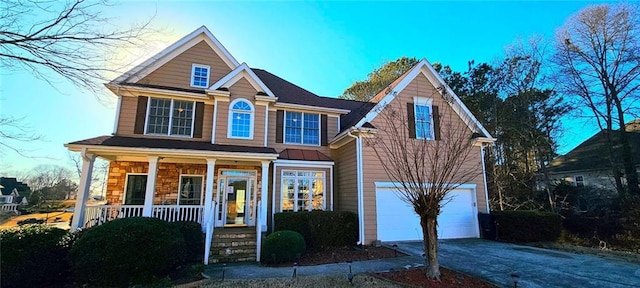 traditional home with driveway, an attached garage, and covered porch
