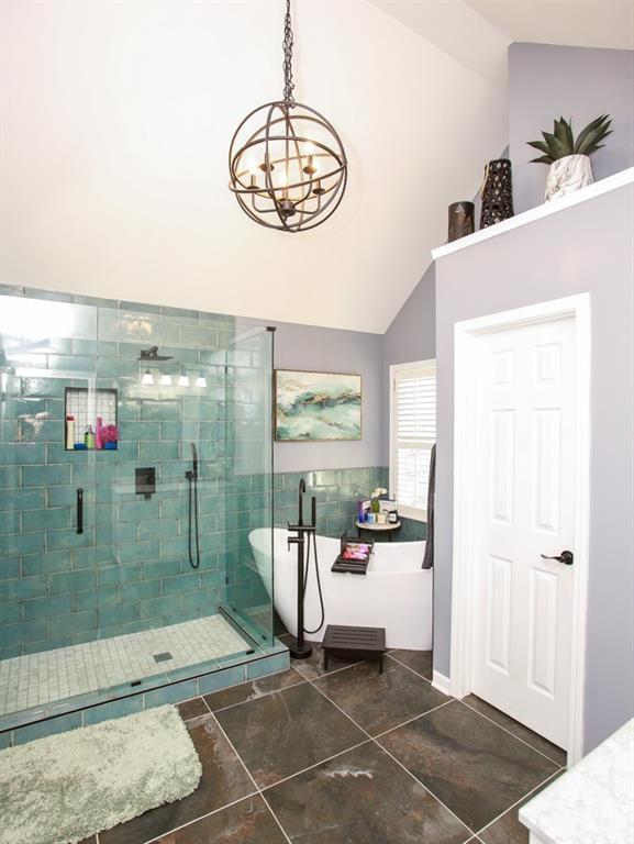 bathroom with an inviting chandelier, tile patterned flooring, a shower stall, a soaking tub, and high vaulted ceiling
