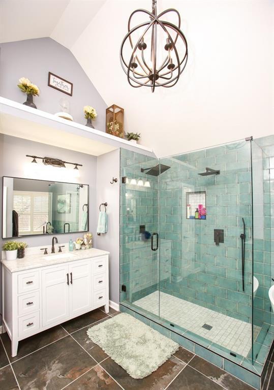 full bathroom featuring a shower stall, vanity, a notable chandelier, tile patterned flooring, and lofted ceiling