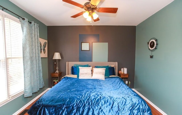 bedroom featuring baseboards, wood finished floors, and multiple windows