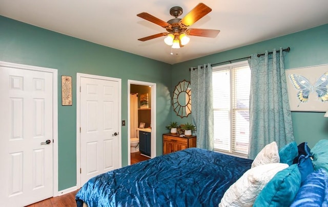 bedroom with wood finished floors, ceiling fan, multiple windows, and ensuite bathroom