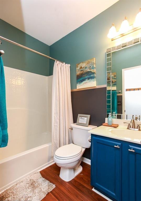 full bath with shower / bathtub combination with curtain, wood finished floors, toilet, and vanity