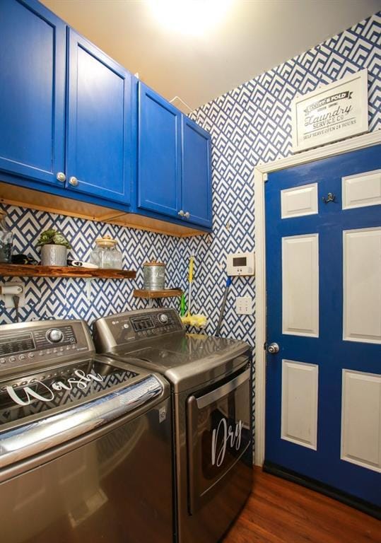washroom featuring dark wood-style floors, wallpapered walls, cabinet space, and washing machine and clothes dryer