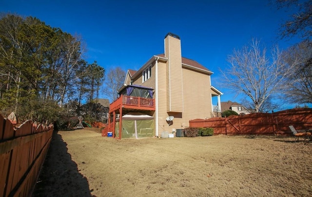 back of house with a chimney, fence private yard, an exterior structure, and central AC