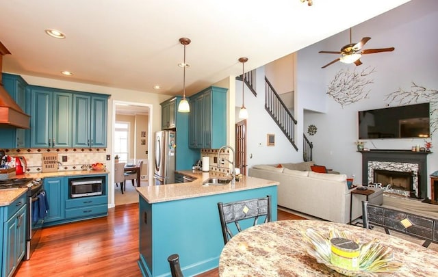 kitchen featuring a sink, ceiling fan, open floor plan, appliances with stainless steel finishes, and wood finished floors
