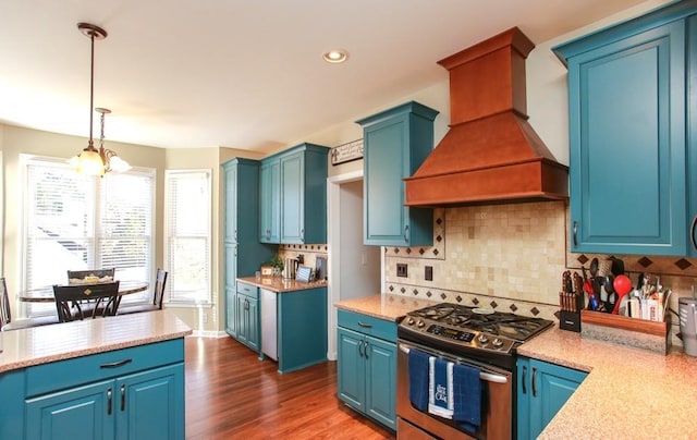 kitchen featuring decorative backsplash, custom exhaust hood, hanging light fixtures, stainless steel gas range oven, and dark wood finished floors