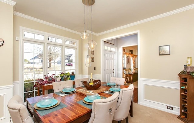 dining space with ornamental molding, a wainscoted wall, and a decorative wall