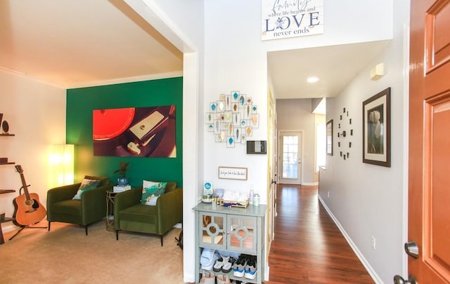 hall featuring wood finished floors, crown molding, and baseboards