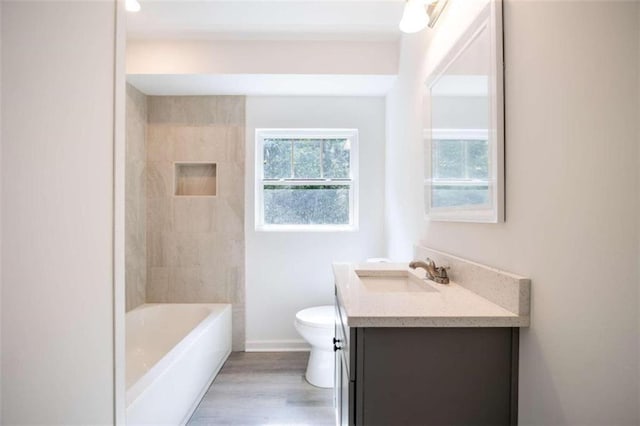 full bathroom featuring vanity, tiled shower / bath, hardwood / wood-style flooring, and toilet