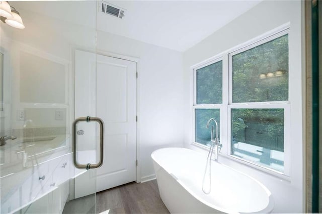 bathroom featuring a tub to relax in and hardwood / wood-style floors