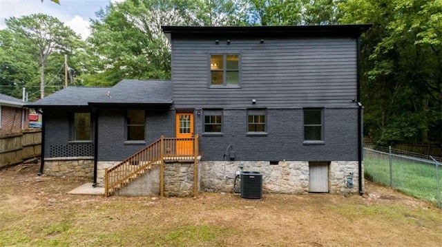 rear view of property featuring central AC and a lawn