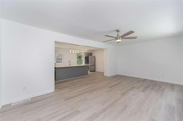 unfurnished living room with sink, ceiling fan, and light hardwood / wood-style flooring