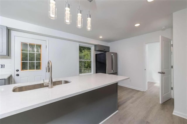 kitchen featuring sink, pendant lighting, gray cabinets, light hardwood / wood-style floors, and stainless steel refrigerator