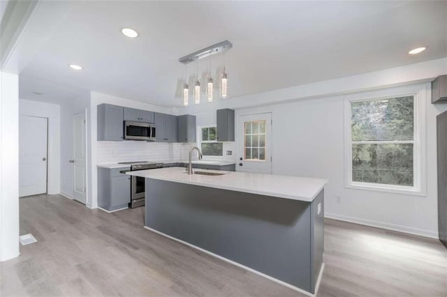 kitchen with stainless steel appliances, sink, a wealth of natural light, and gray cabinets