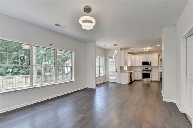 unfurnished living room featuring dark hardwood / wood-style floors, a notable chandelier, and sink