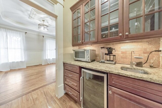 bar featuring sink, wine cooler, light stone counters, light hardwood / wood-style flooring, and a tray ceiling