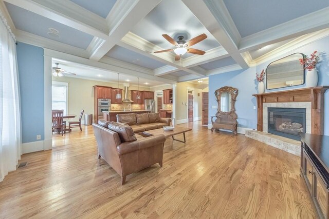 living room featuring beamed ceiling, a tile fireplace, and coffered ceiling