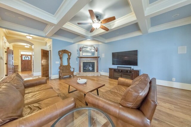 living room with beam ceiling, ceiling fan, a fireplace, and light hardwood / wood-style floors