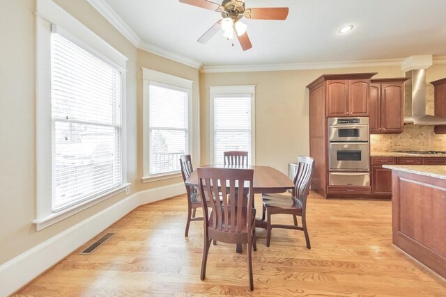 dining space with ceiling fan, crown molding, and light wood-type flooring