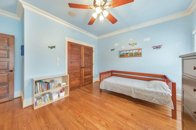 bedroom with a closet, light hardwood / wood-style flooring, ceiling fan, and ornamental molding