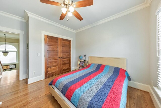 bedroom with hardwood / wood-style floors, ceiling fan, crown molding, and a closet